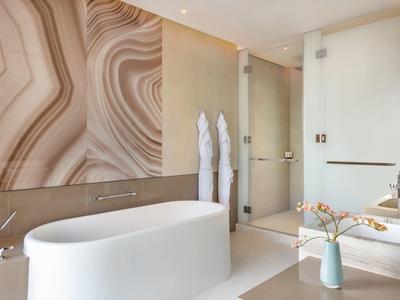 Modern hotel bathroom with freestanding bathtub and decorative wall design
