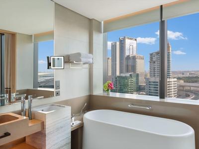 Modern bathroom with freestanding bathtub and large window overlooking the city.