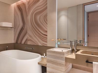 Modern bathroom with freestanding bathtub, large mirror, and subtle lighting.