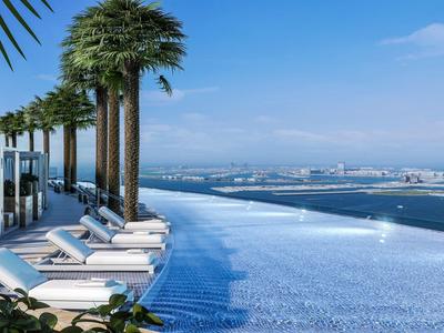 Infinity pool with white loungers and palm trees, overlooking coast and sea on a sunny day