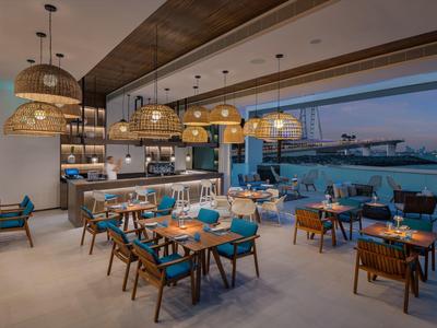 Modern restaurant with wood details and harbor view at sunset.