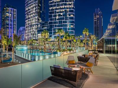 Salon extérieur moderne avec chaises et tables devant des gratte-ciel illuminés la nuit