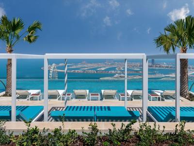 Espace piscine de luxe avec chaises longues et vue sur l'océan sous un ciel clair