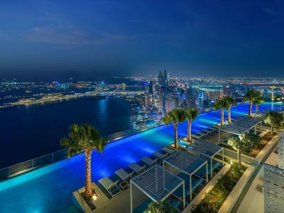 Infinity pool on rooftop terrace overlooking a lit city at night