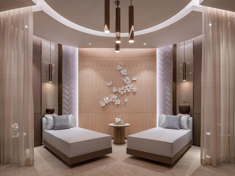 Elegant relaxation room with two loungers, wall plant art, and soft lighting.