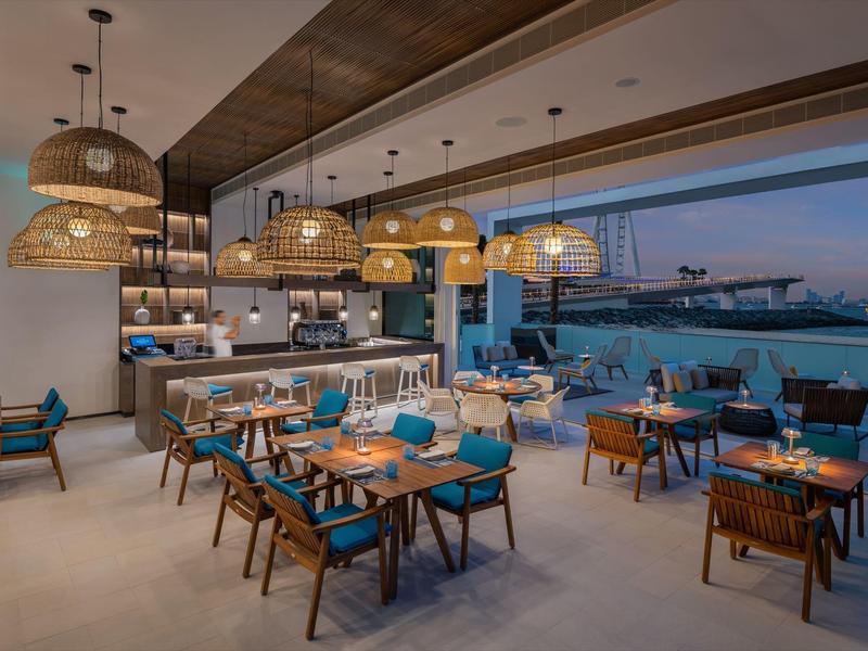 Modern restaurant with wood details and harbor view at sunset.