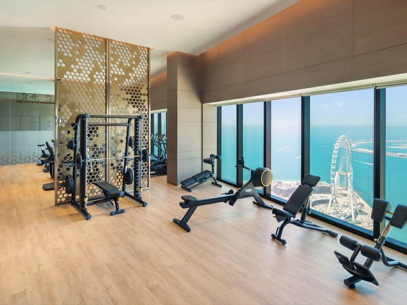 Bright gym with large windows overlooking the sea and a Ferris wheel.