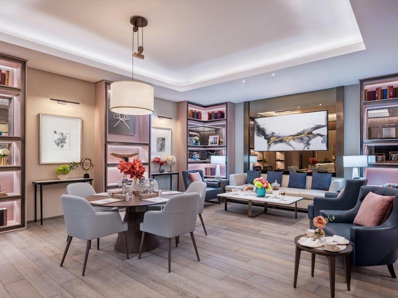 Modern living room with dining table, armchairs, and bookshelves in a stylish setting.