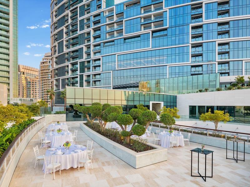 Outdoor terrace with elegant white tables and chairs in front of modern glass buildings