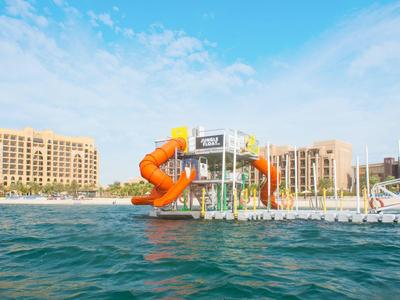 Wasserrutsche an einem Hotelpool mit Blick auf das Meer und Gebäude im Hintergrund.