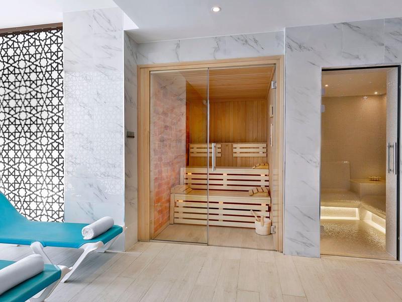 Moderner Wellnessbereich mit Sauna, Dampfbad, blauen Liegestühlen und Marmorwänden.