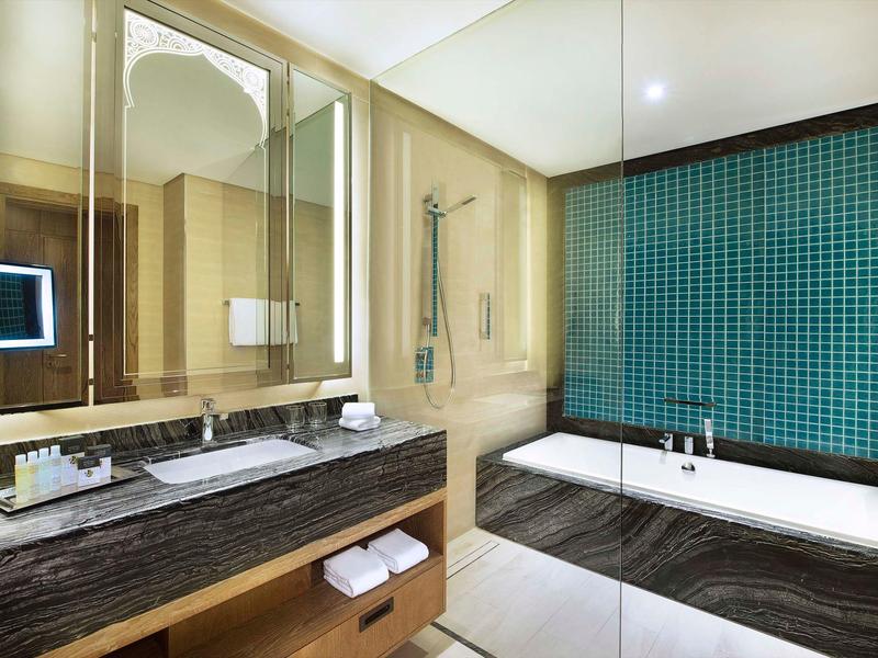 Elegantes Badezimmer mit großer Badewanne, Mosaikfliesen und Holzoptik-Arbeitsfläche.