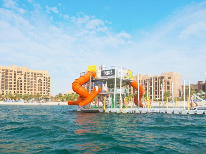 Wasserrutsche und Plattform im Meer vor Hotelgebäuden an einem sonnigen Tag