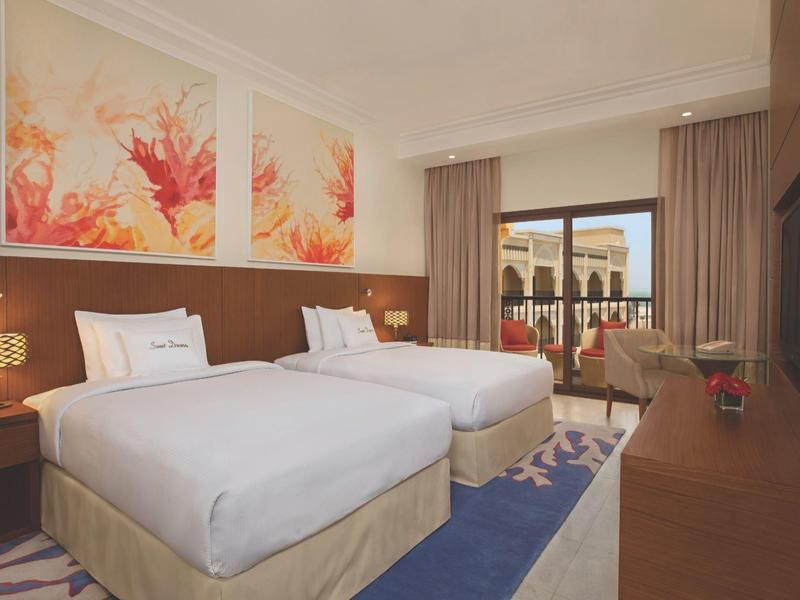 Modernes Hotelzimmer mit zwei Einzelbetten, Balkon und Stadtblick.