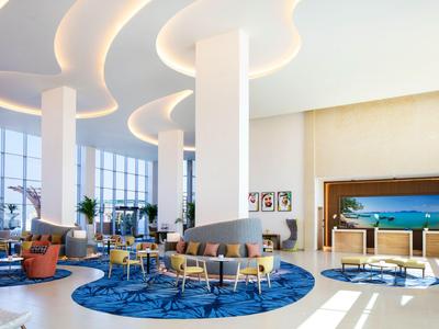 Amplio y moderno vestíbulo de hotel con techos curvos, alfombra azul y áreas de descanso cómodas.