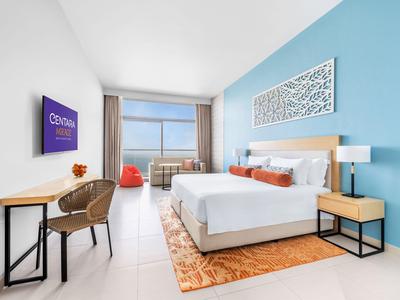 Habitación de hotel moderna con cama grande, escritorio, área de estar e interior luminoso.