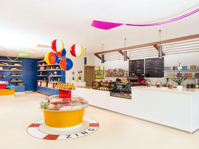 Café de hotel moderno y luminoso con decoraciones coloridas y mostrador de venta amplio.