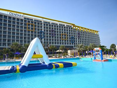 Un hotel con una gran piscina y estructuras inflables bajo un cielo despejado.