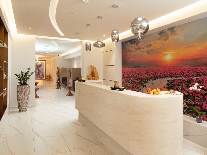 Moderne hotellobby met helder ontvangstbalie en wandkunst van een zonsondergang over bloemen.
