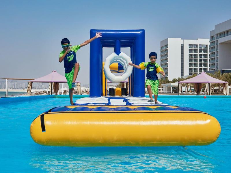 Twee kinderen spelen op een opblaasbare waterhindernis in een hotelzwembad.