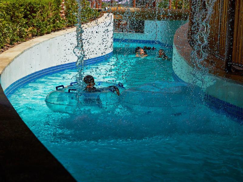 Twee mensen ontspannen in een buitenzwembad met bruisend water en decoratieve kettingen.