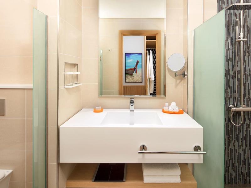 Moderne badkamer met brede witte wastafel, spiegel en douchegedeelte.