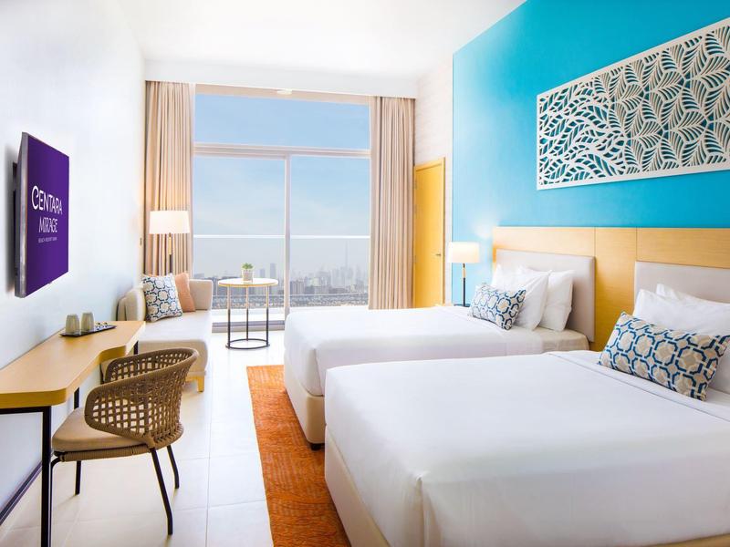 Moderne hotelkamer met twee bedden, bureau, balkon met uitzicht en decoratieve wandkunst.