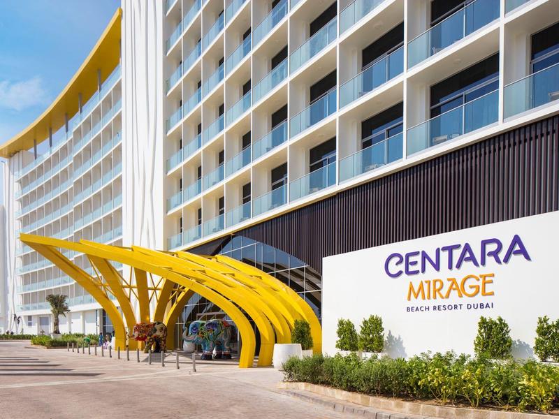 Modern hotel met gele luifel en grote ingang bij heldere lucht.