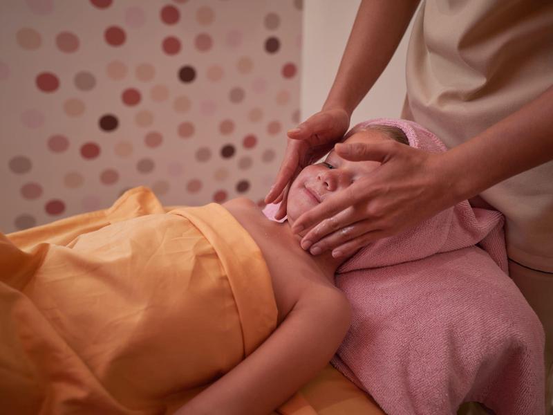 Persoon krijgt gezichtsbehandeling in een ontspannende spa met warme kleuren.