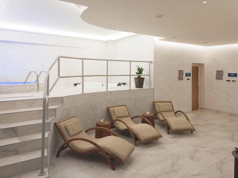 Moderne spa-lounge met ligstoelen en toegang tot een verwarmd zwembad.