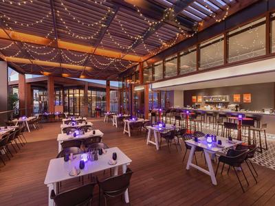 Elegant hotel restaurant with illuminated tables and covered terrace at dusk.