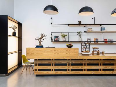 Modern hotel reception with wooden counter, chairs, and decorative shelves on the wall.