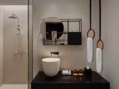 Modern bathroom with round mirror, white sink, and shower with glass partition.