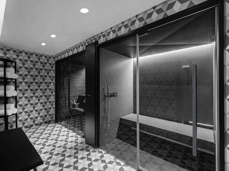 Modern wellness area with steam bath, bench, and patterned tiles.