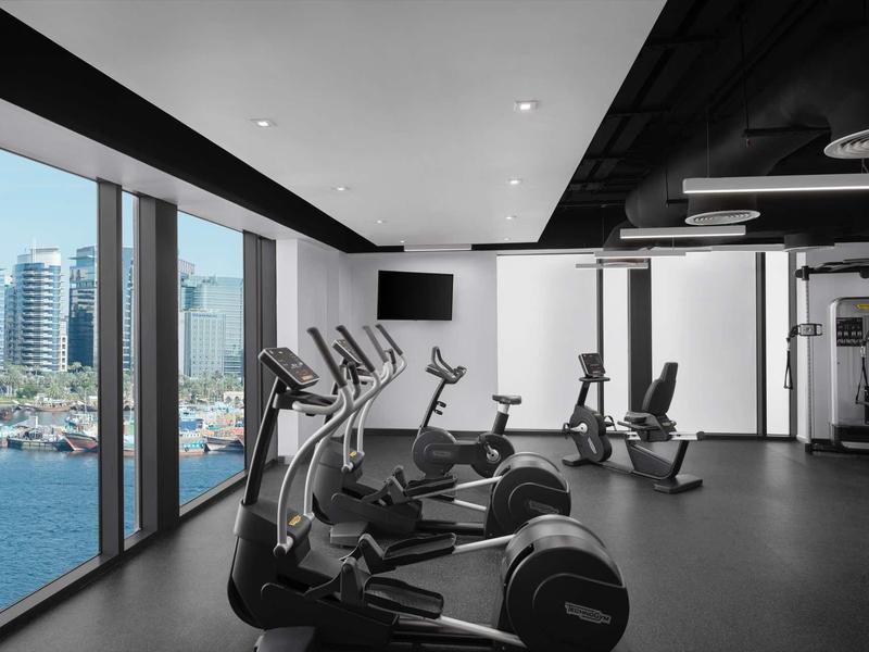 Modern gym with cardio equipment and large windows overlooking the harbor.
