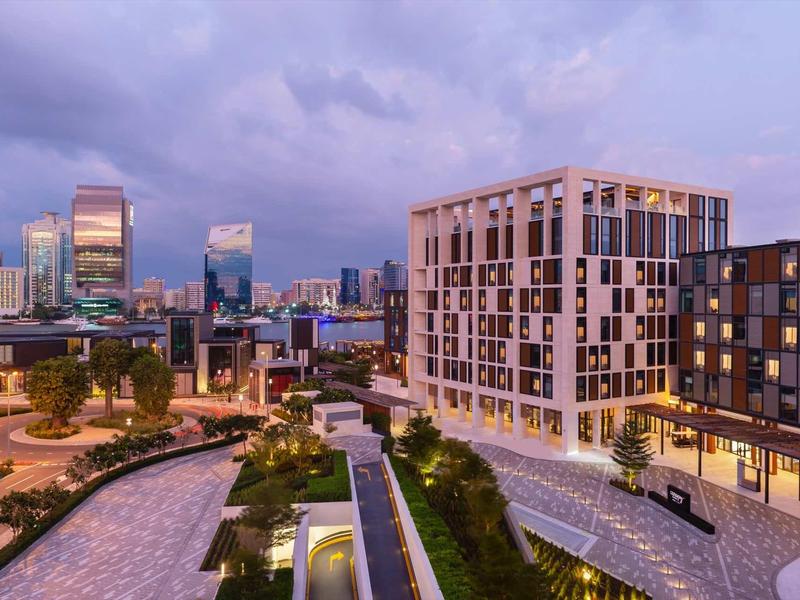 Modern hotel complex with adjacent green spaces and city center at dusk
