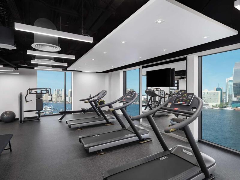 Modern hotel gym with treadmills and city view through large windows