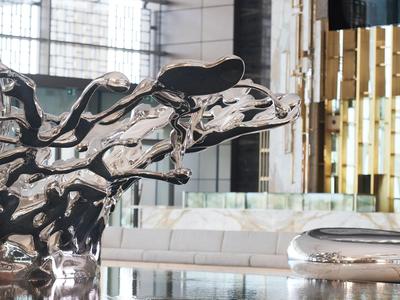 Abstrakcyjna błyszcząca rzeźba w nowoczesnym, jasnym wnętrzu z szkłem i drewnem