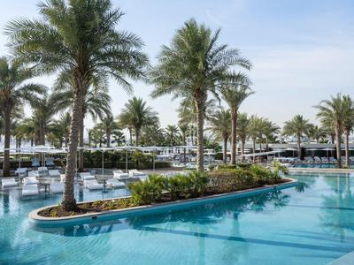 Basen z palmami i leżakami pod czystym niebem.