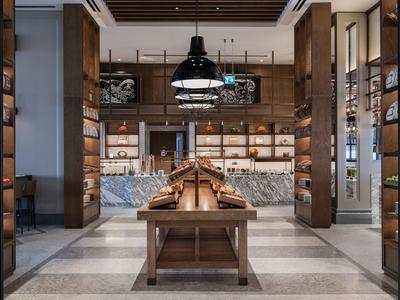 Moderner Innenraum mit Holzregalen, Marmortresen und hängenden Lampen in warmem Licht.