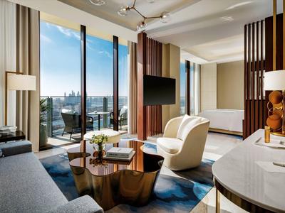 Modern gestaltetes Hotelzimmer mit Sofa, Sesseln und großer Fensterfront mit Stadtblick.