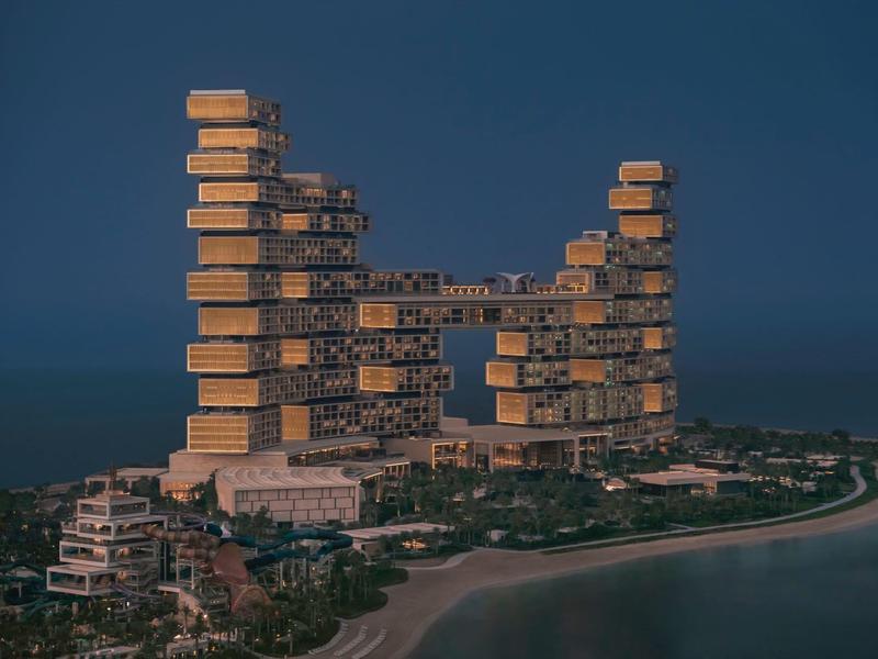 Großes, modernes Gebäude mit rechteckigen, gestapelten Blöcken an einer Küste bei Dämmerung.