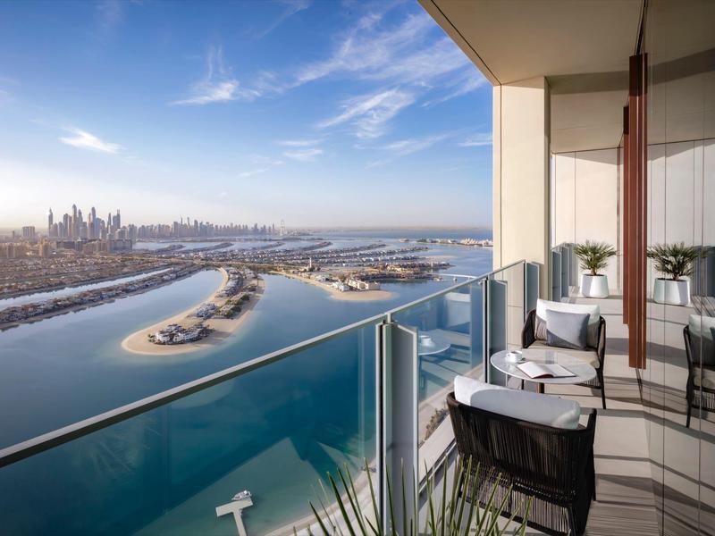Balkon mit Stühlen und Tischen bietet Blick auf Fluss, Inseln und Skyline bei klarem Himmel.