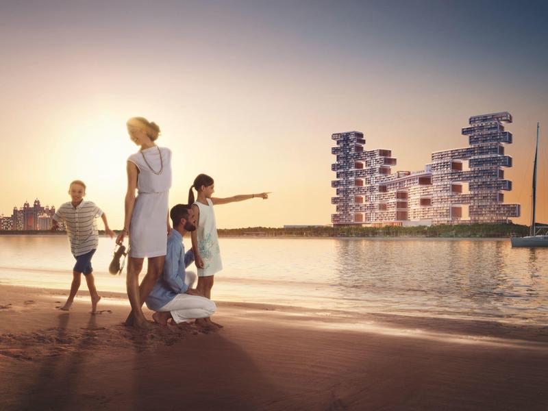 Familie am Strand bei Sonnenuntergang, moderne Architektur auf dem Wasser im Hintergrund.