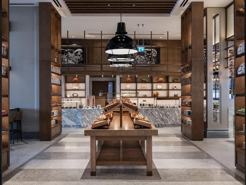 Moderner Innenraum mit Holzregalen, Marmortresen und hängenden Lampen in warmem Licht.