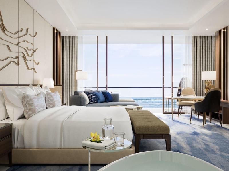 Modernes Hotelzimmer mit großem Bett, stilvoller Wanddekoration und Meerblick durch bodentiefe Fenster.