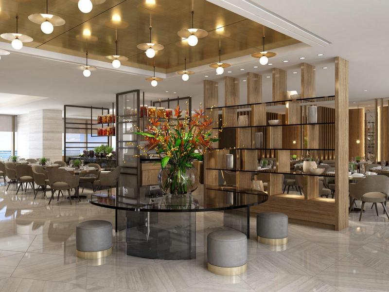 Großer, heller Gastraum mit modernen Tischen, Stühlen, integriertem Holzregal und hängenden Lampen.