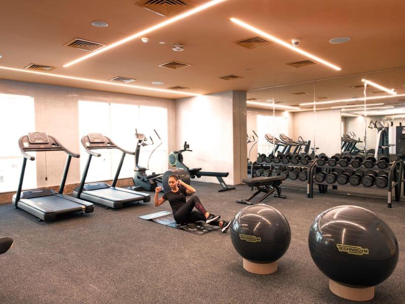 Modern gym with treadmills, dumbbells, and exercise balls in a bright room.