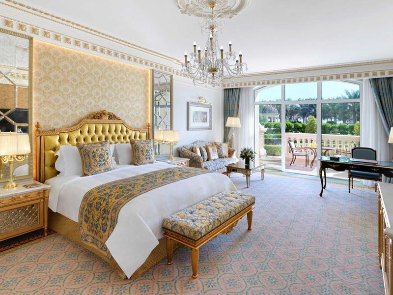 Luxuriöses Schlafzimmer mit goldverziertem Bettrahmen, Kronleuchter und großem Balkonfenster.