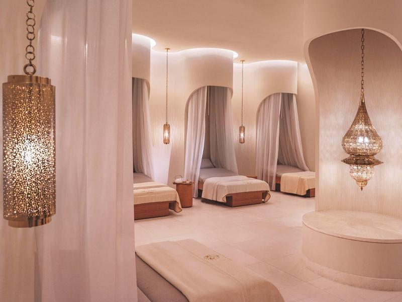 Helles, modernes Spa mit sanfter Beleuchtung, runden Wänden, Stoffvorhängen und eleganten Hängelampen.